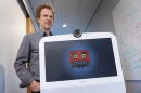 Professor Matthias Scheutz follows AVA along a hallway at the Human Robot Interaction Lab, at Tufts University.  (Robin Lubbock/WBUR)
