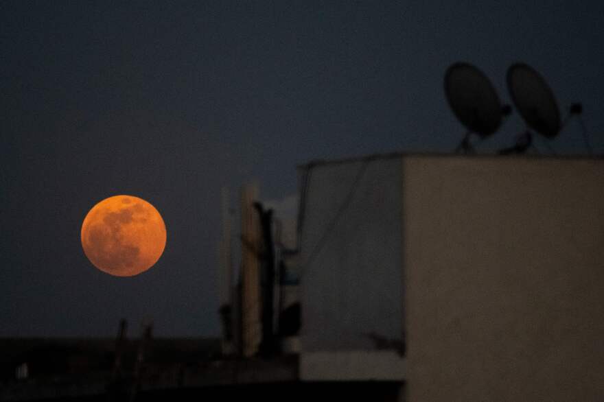 The Super Blood Moon rises over a residential area in New Delhi during a total lunar eclipse on May 26, 2021.