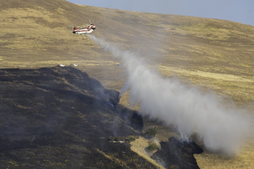 A helicopter drops water on a fire burning on Mount Sentinel in Missoula, August 20, 2020.