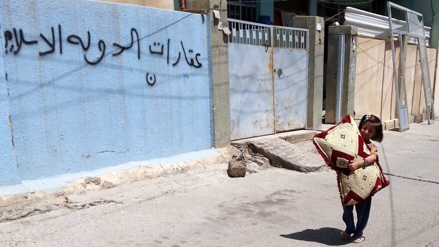 An Iraqi child walks next an empty house of a Christian family in Mosul on Aug. 8. The Arabic writing on the wall reads "Real Estate of the Islamic State." The extremist group took control of Mosul, Iraq's second largest city, in June.