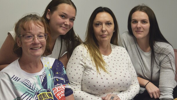 A group of four women sit together for a photo.
