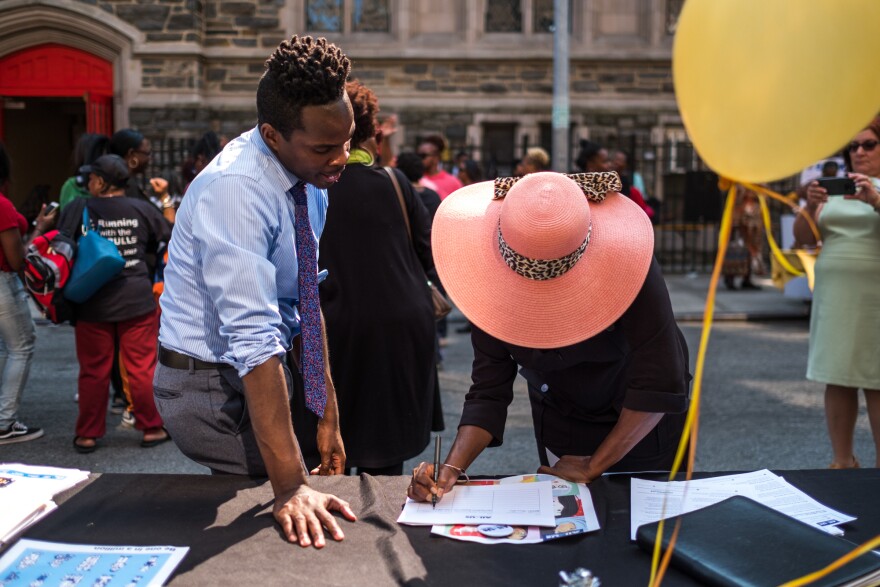 Kolbi Brown (left), a program manager at Harlem Hospital, helps Karen Phillips sign up to receive more information about the "All of Us" medical research program, during a block party outside the Abyssinian Baptist Church in Harlem.