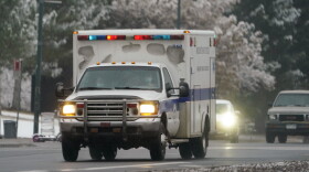 An ambulance roars along westbound West Colfax Avenue through traffic in downtown Denver. (David Zalubowski/AP)