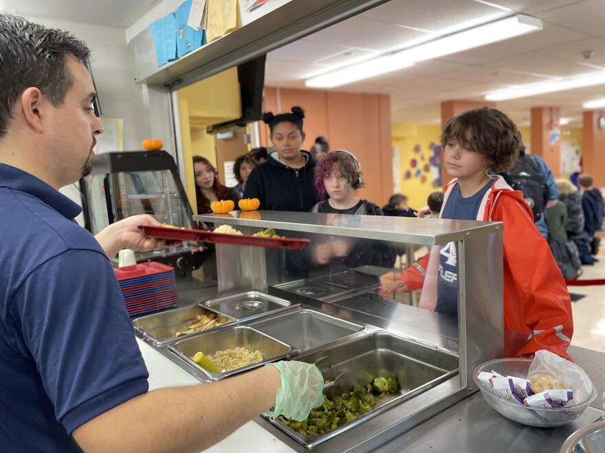 Andrew Bernard serving chicken satay with rice and sauteed broccoli to Provincetown students.