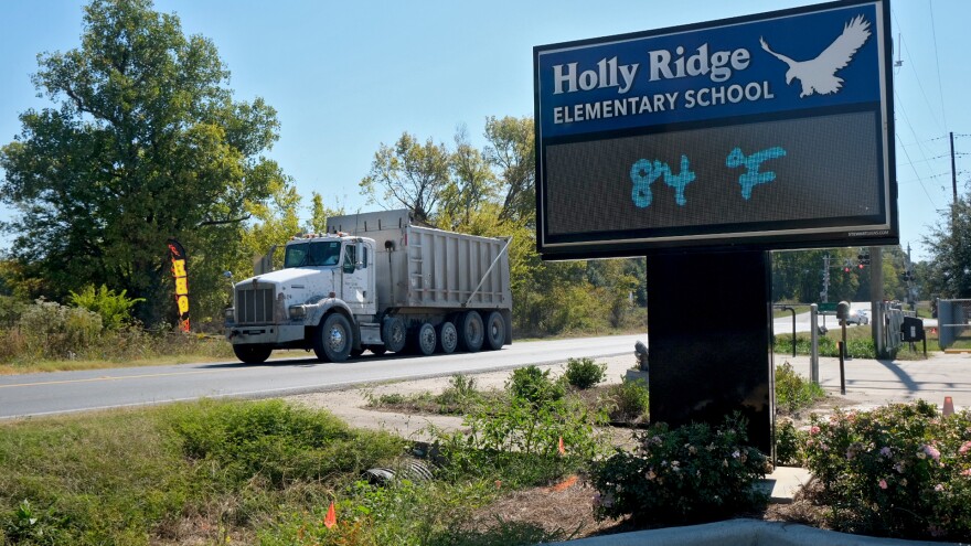 A dump truck drives past Holly Ridge Elementary School in Holly Ridge, Louisiana, on Friday, October 17, 2025. The school is less than a mile away from the construction site of Meta’s new data center, Hyperion. Officials shut down the playground in front of the school because of safety concerns related to the truck traffic.