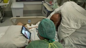 A nurse talks to the family of a patient using a tablet inside a negative pressure room  on April 10, 2020, during her night shift in the intensive care unit exclusively for COVID-19 patients in Brussels. (Aris Oikonomou/AFP/Getty Images)