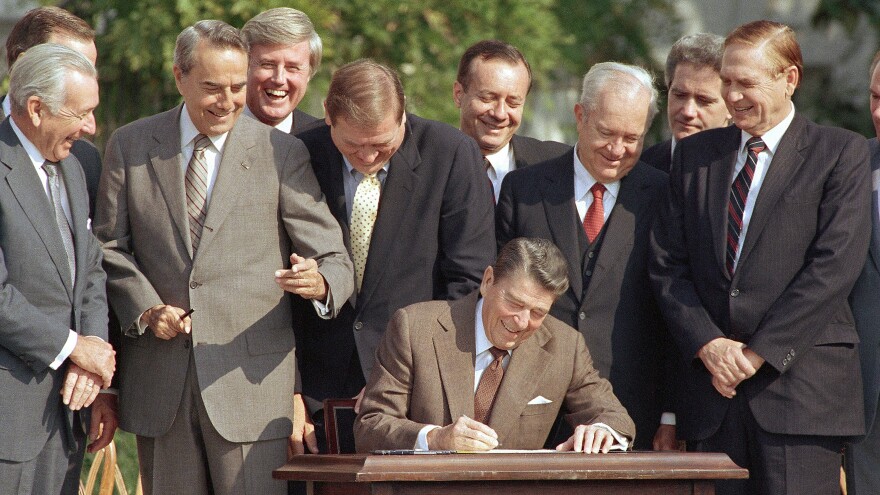 Lawmakers watch as President Ronald Reagan signs into law a landmark tax overhaul in October 1986.