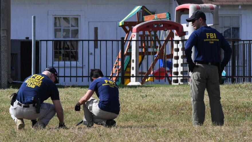 FBI agents search for clues Monday beside a playground near the First Baptist Church in Sutherland Springs, Texas.