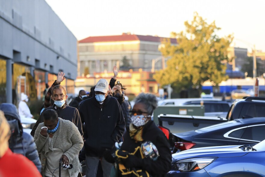 People stand in line at the Hamilton County Board of Elections to participate in early voting, Tuesday, Oct. 6, 2020, in Norwood.