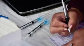 A worker at a COVID-19 vaccination clinic fills out paperwork.