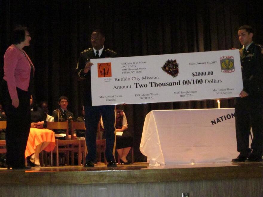 City Mission's Sue Cervi (left) accepts a check from representatives of the Jr. ROTC at McKinley High School.