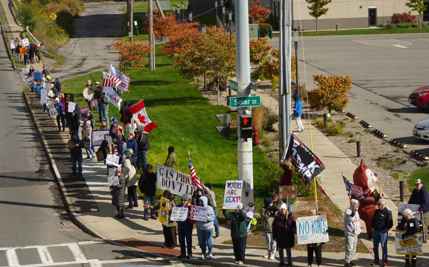 Ralliers stand at the street corner of Hiawatha Blvd. and Solar Street in Syracuse holding signs urging passersby to vote early.