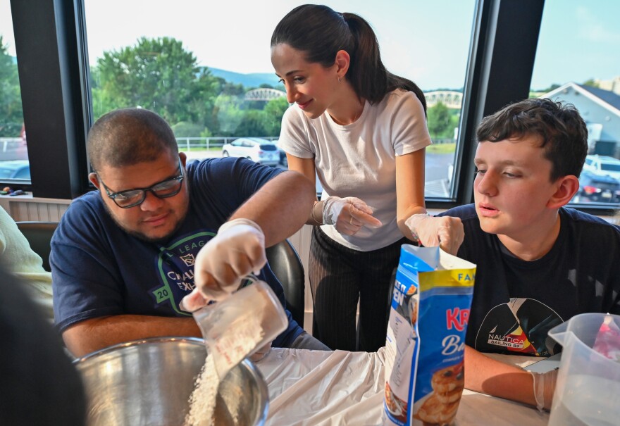 Aiden Thomas and Alex Clark work with University student Christina preparing the pancake batter.