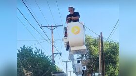 A cable worker in a lift working on power lines.