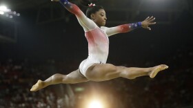 Simone Biles, a 4'8" package of muscle, performs at an Olympic exhibition gala after having won four gold medals and one bronze in the 2016 Games. What she is wearing is not relevant.