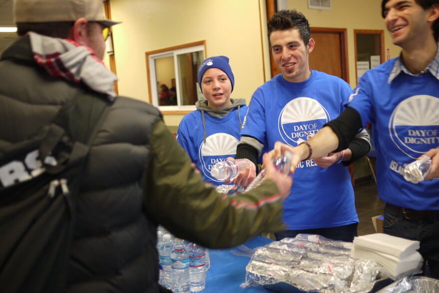 Syrian refugees Yazan Al-Salkini, 19, center, and brother Nabil, 14, left, hand out water to the homeless in downtown Seattle.
