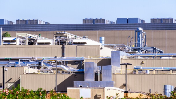 Exterior of a data center with rooftop equipment, exposed pipes and large metal ducts in Silicon Valley, South San Francisco Bay Area, California.