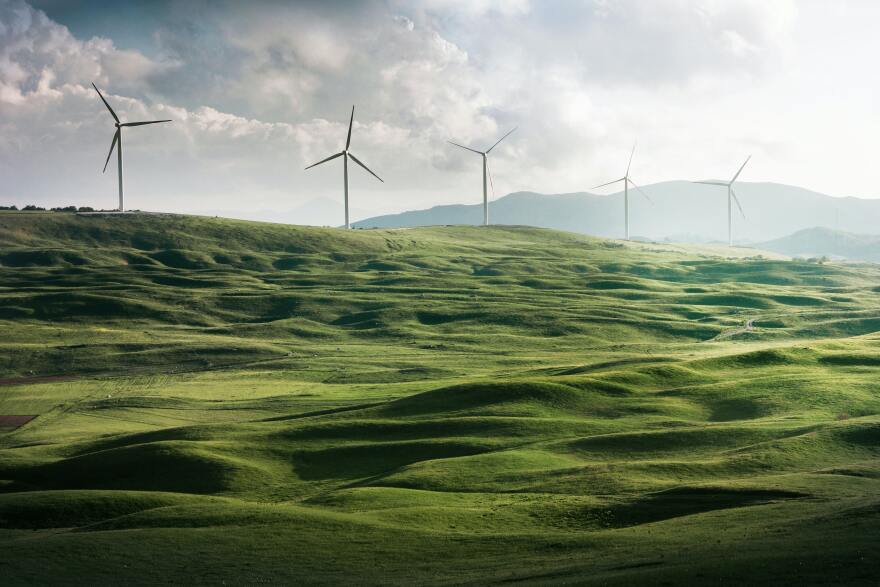 Five windmills on grassy hills.