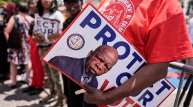A protestor holds a sign of the late Georgia Congressman John Lewis during a voting rally, Saturday, May 16, 2026, in Montgomery, Ala. (AP Photo/Mike Stewart)