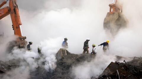 Firefighters make their way over the ruins of the World Trade Center through clouds of smoke at ground zero in New York.