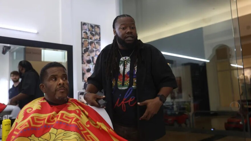 John "Speedy" Riddle pauses Jermaine Moore's haircut to discuss his life in Houston after Hurricane Katrina.