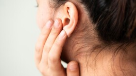 closeup on woman's ear as she presses on the lobe with her fingers 