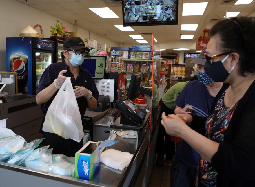 Shop owner Si Nguyen rings up customers in his Frogtown market in St. Paul, Minn.