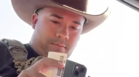 An unidentified Immigration and Customs Enforcement officer examines the driver's license of Dodge City, Kansas, resident Guadalupe Navarrete on Sept. 23, 2026. Navarrete was driving with her father Frank Duran. They were not detained.