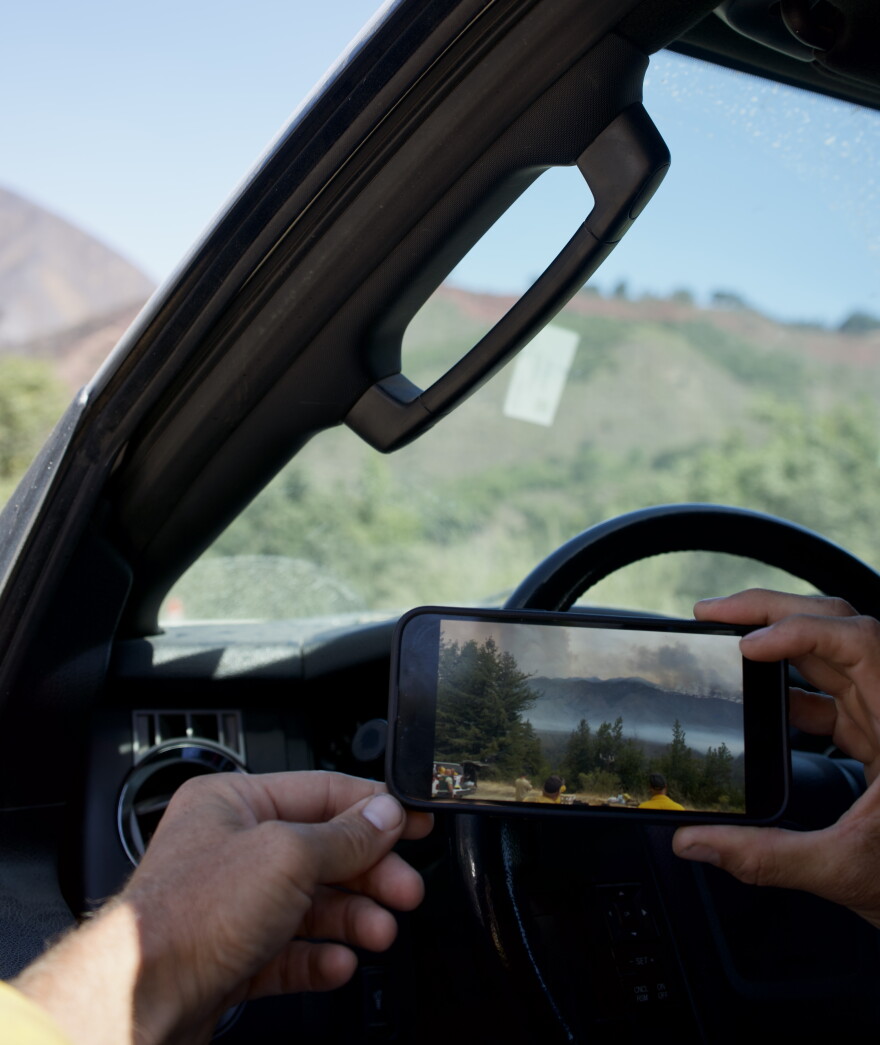 A man holds a phone in his hand with a picture of a burning fire. 