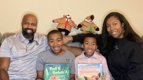 Michael Womack (middle left) and Gabriel Womack (middle right) with their parents and holding their books