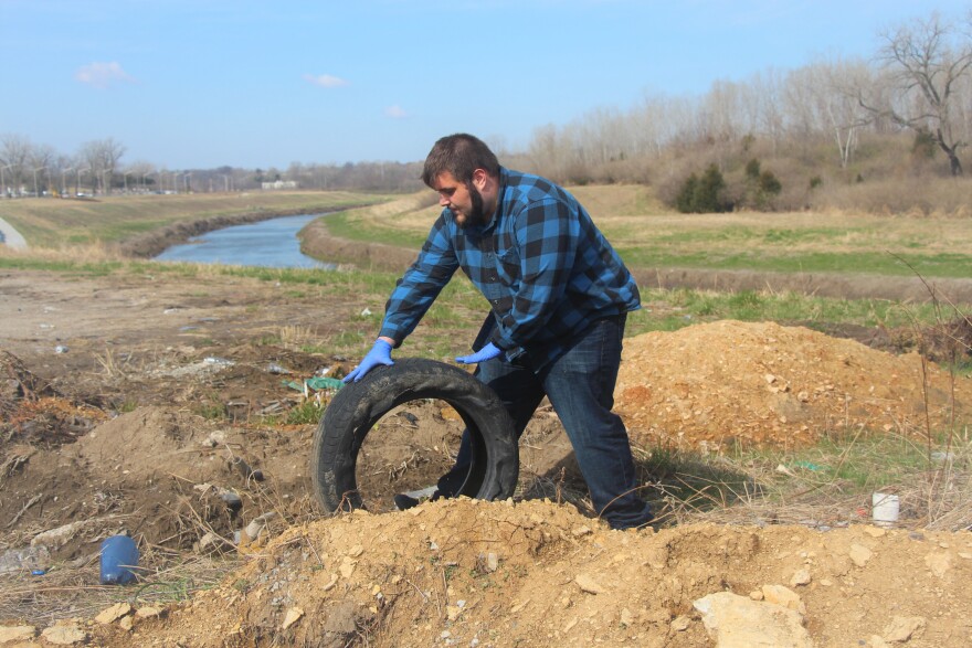 A photo shows Biology student Joseph Kempinger gathering illegally dumped trash along the Blue River last April.