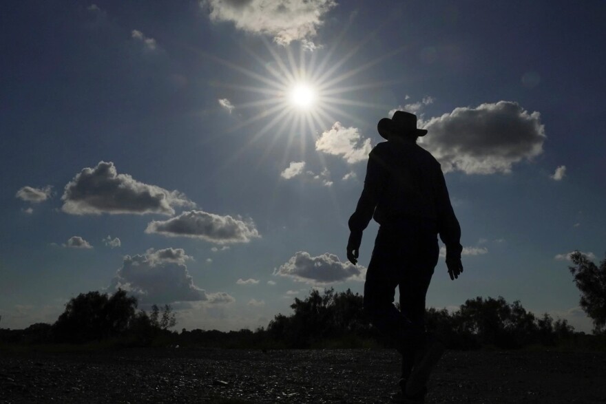 Kayak and canoe outfitter Jessie Fuentes walks along the Rio Grande under a warm sun Thursday, July 6, 2023. As the heat breaks records, weakening and sickening people, it’s worth remembering that dire heat waves have inspired effective efforts to prevent heat illness.