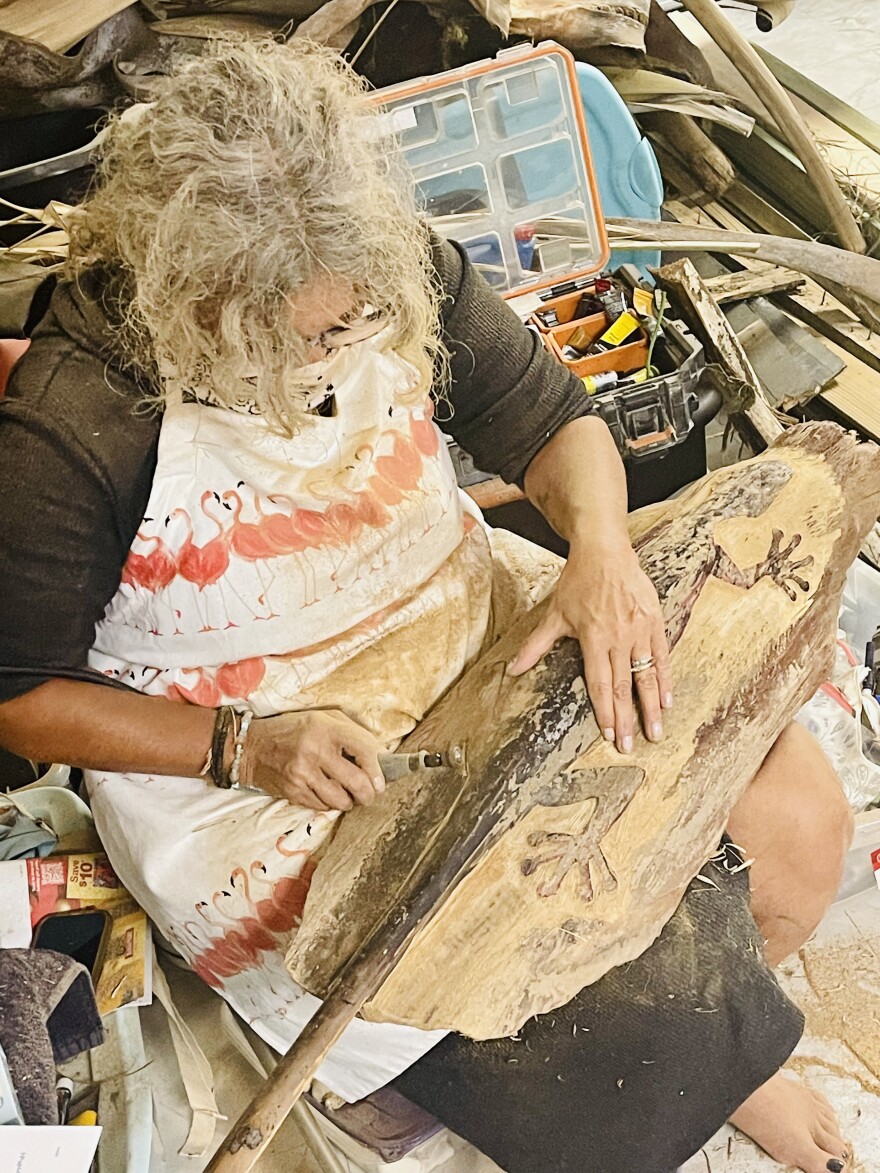 Gretchen Kilburn works on a piece of wood found after Hurricane Ian.