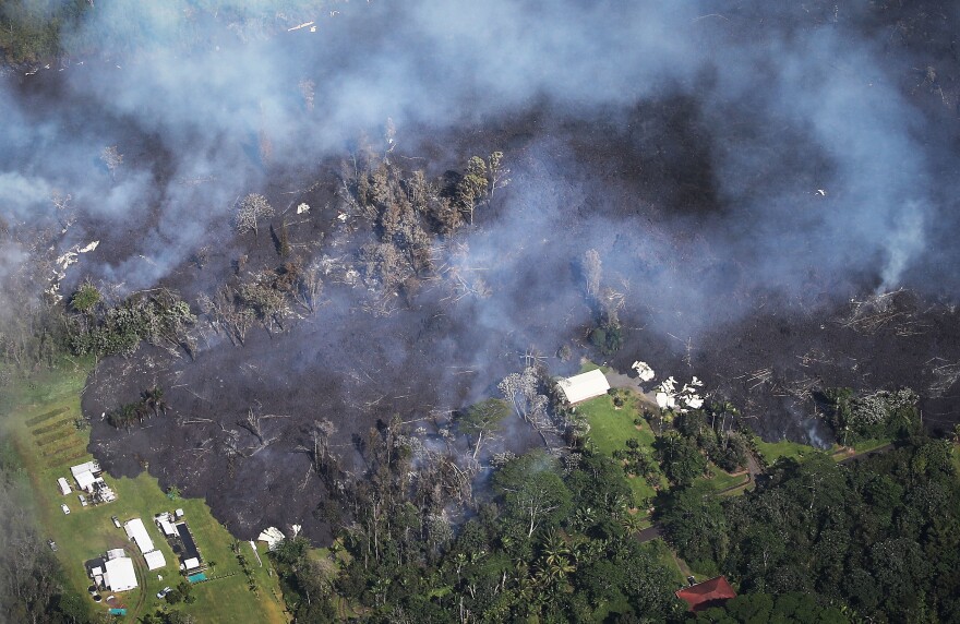 Lava from volcanic fissures slowly advances and overtakes structures and trees in the Leilani Estates neighborhood on Sunday. At least 26 homes have been destroyed by lava.