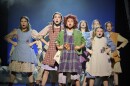 eight girl dressed as orphans in "Annie" are singing with hands on their hips