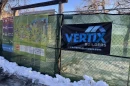 A green chain link fence at the Denver Zoo bears a map of the zoo and a sign for Vertix Builders. 