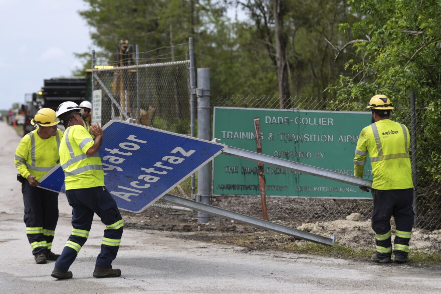 Workers install a sign reading "Alligator Alcatraz" at the entrance to a new migrant detention facility at Dade-Collier Training and Transition facility, Thursday, July 3, 2025, in Ochopee, Fla. (AP Photo/Rebecca Blackwell)
