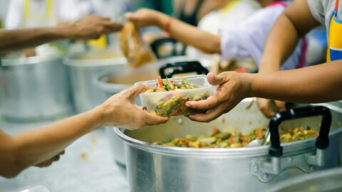 Large pots of mixed food, and hands passing a container with food in it to others' hands