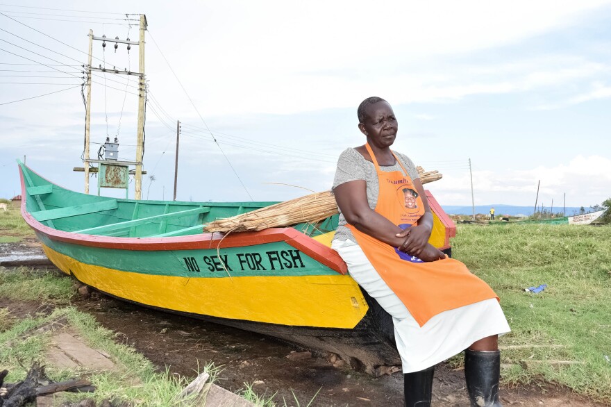 Justine Adhiambo Obura with one of the "No Sex for Fish" boats at Nduru beach. She is the chairperson of the cooperative that came up with a radical idea in a community where fishermen often demanded transactional sex before giving a supply of fish to a woman to sell: What if women had their own boats and hired men to fish for them?