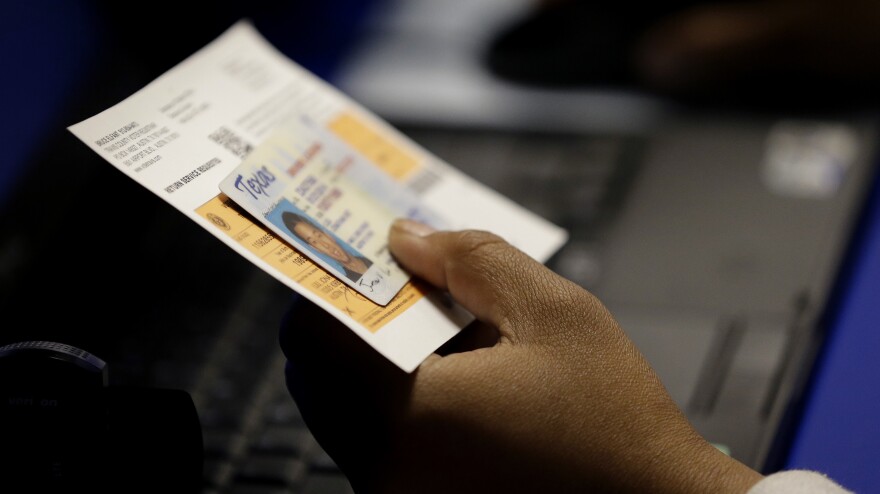 An election official checks a voter's photo identification at a polling site in Austin, Texas.