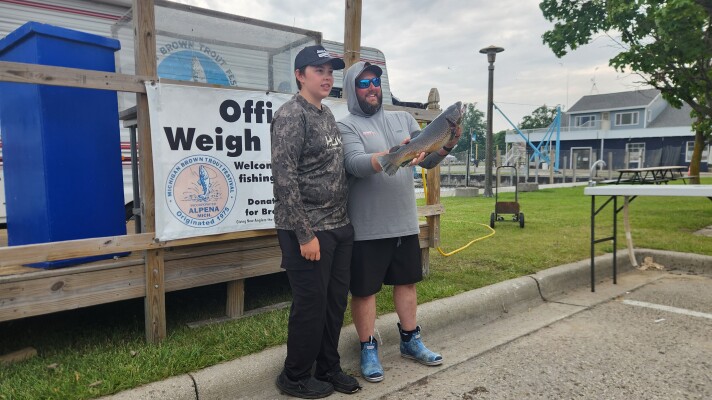 Ryder Wade (left) and Scott Wade (right) pose at the weighing station after catching Big Brownie during the Brown Trout Festival in Alpena, Michigan on Monday, July 20.