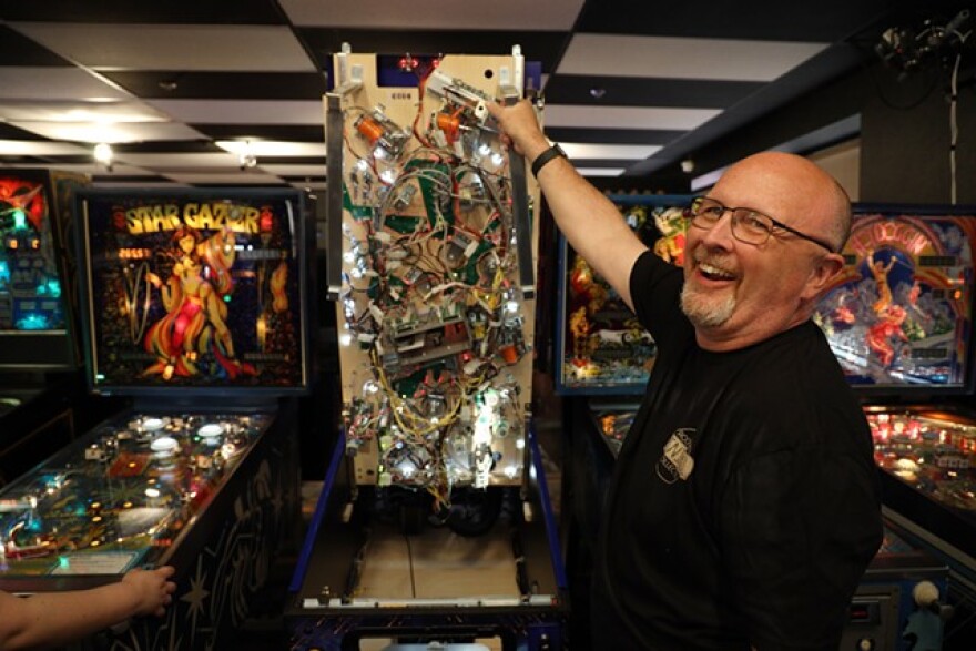 Bruce Nightingale displays the guts of a modern pinball machine. More than half the machines at Rochester Pinball Collective are from his personal collection.