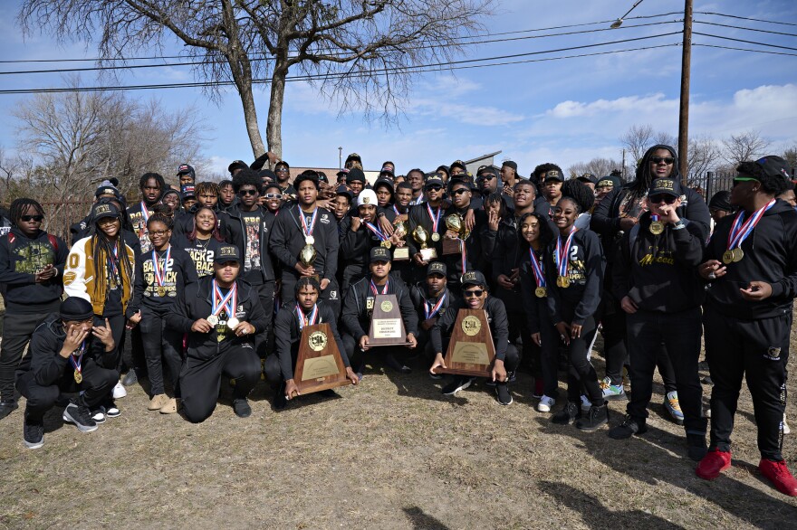Students and football players stand together in a shared moment after celebratory parade hosted by non-profit organization For Oak Cliff.