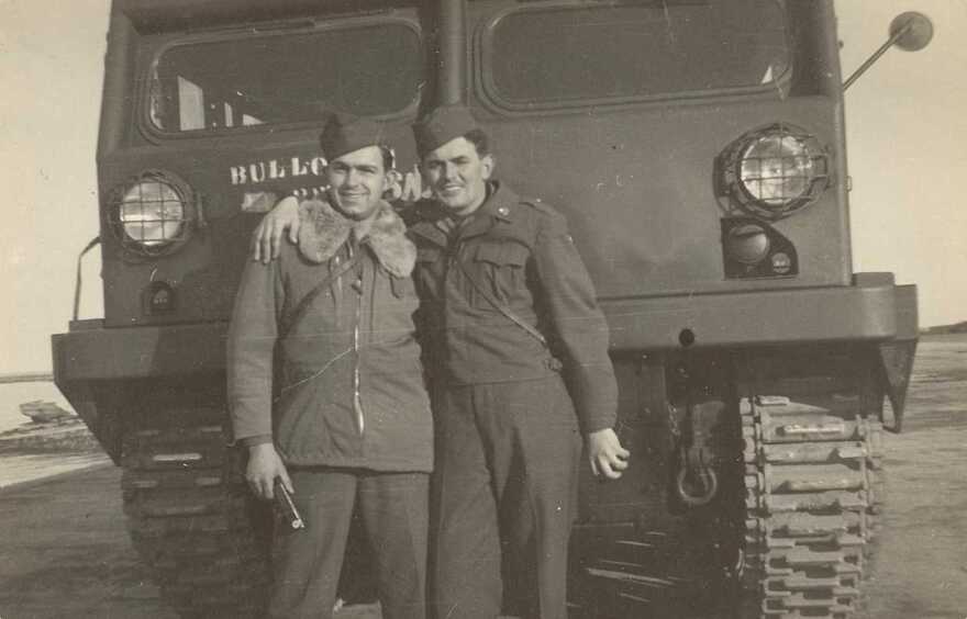Wesley Zacharias and friend dressed in uniform in front of a truck
