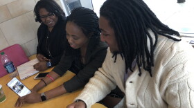 Ifeolu Claytor, 23, (right) and Gabrielle Jackson, 28, (far left) check out a social media voting video on Esosa Osa's phone. All three are members of the Northeast Ohio Young Black Democrats.