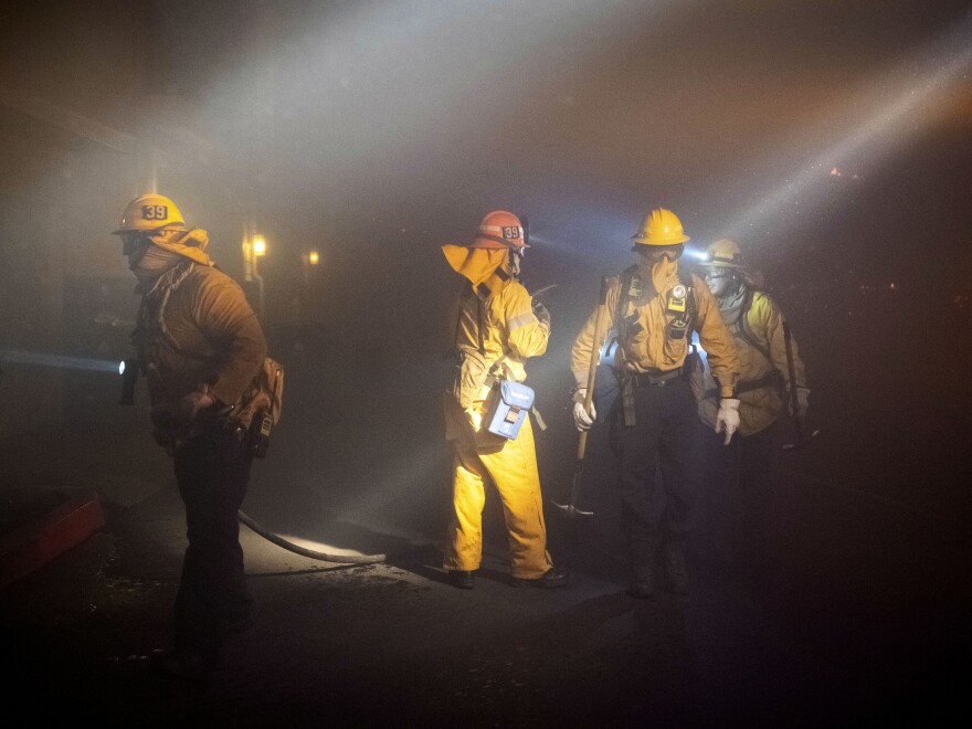 Firefighters check on homes in smoke from the Saddleridge Fire in Sylmar, Calif.