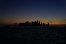 The sun sets behind the West Bay skyline in Doha, Qatar, Monday, Nov. 28, 2022. (AP Photo/Matthias Schrader)