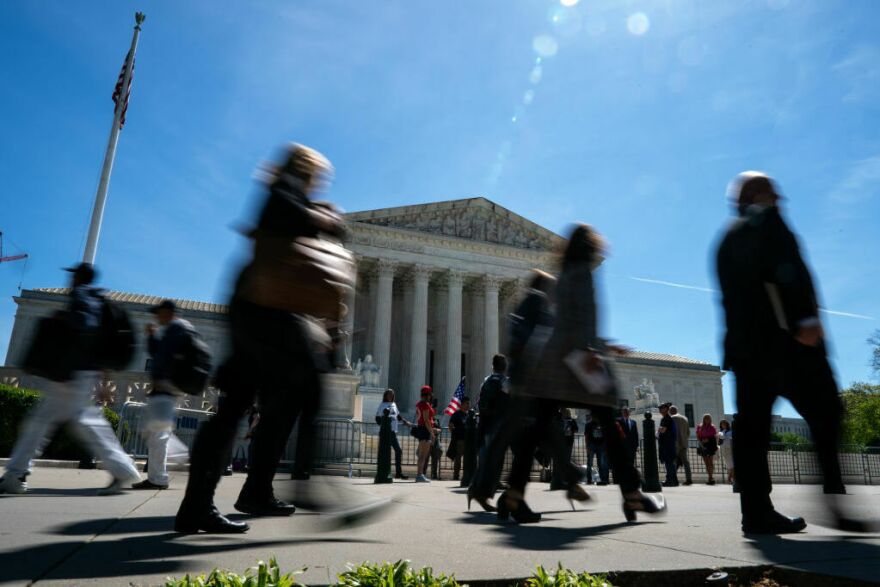 People walk by as supporters of Jan. 6 defendants gather outside of the Supreme Court on Tuesday.