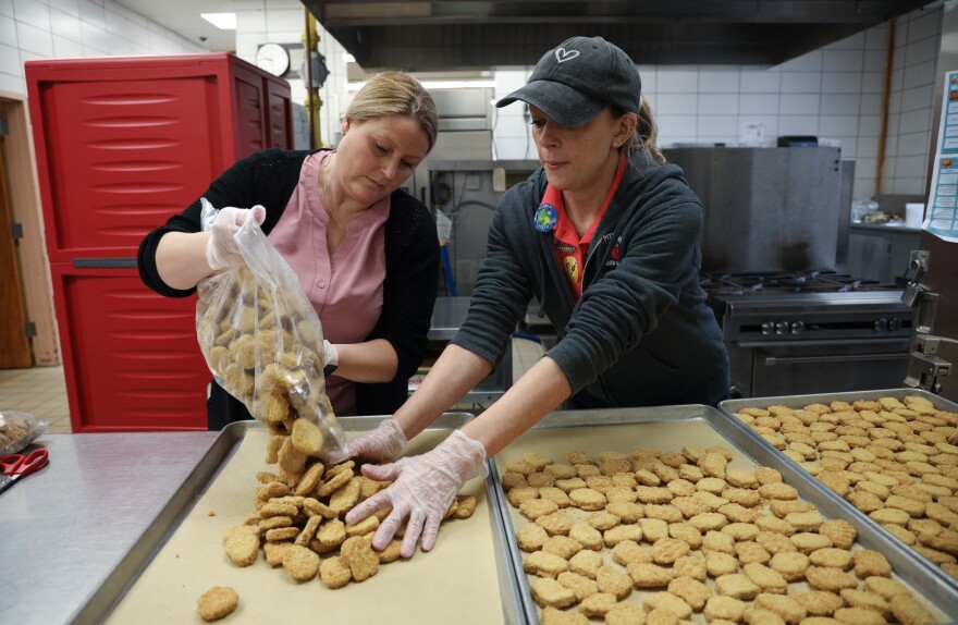 Elena Montgomery, director of food services, and Jessica Hafner-Ventura, cook manager, prepare chicken nuggets for lunch at Park Road Elementary School in Pittsford.