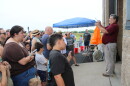 A man stands in front of a crowd holding a weather instrument. He is explaining to the crowd weather balloons work right before he launches one.